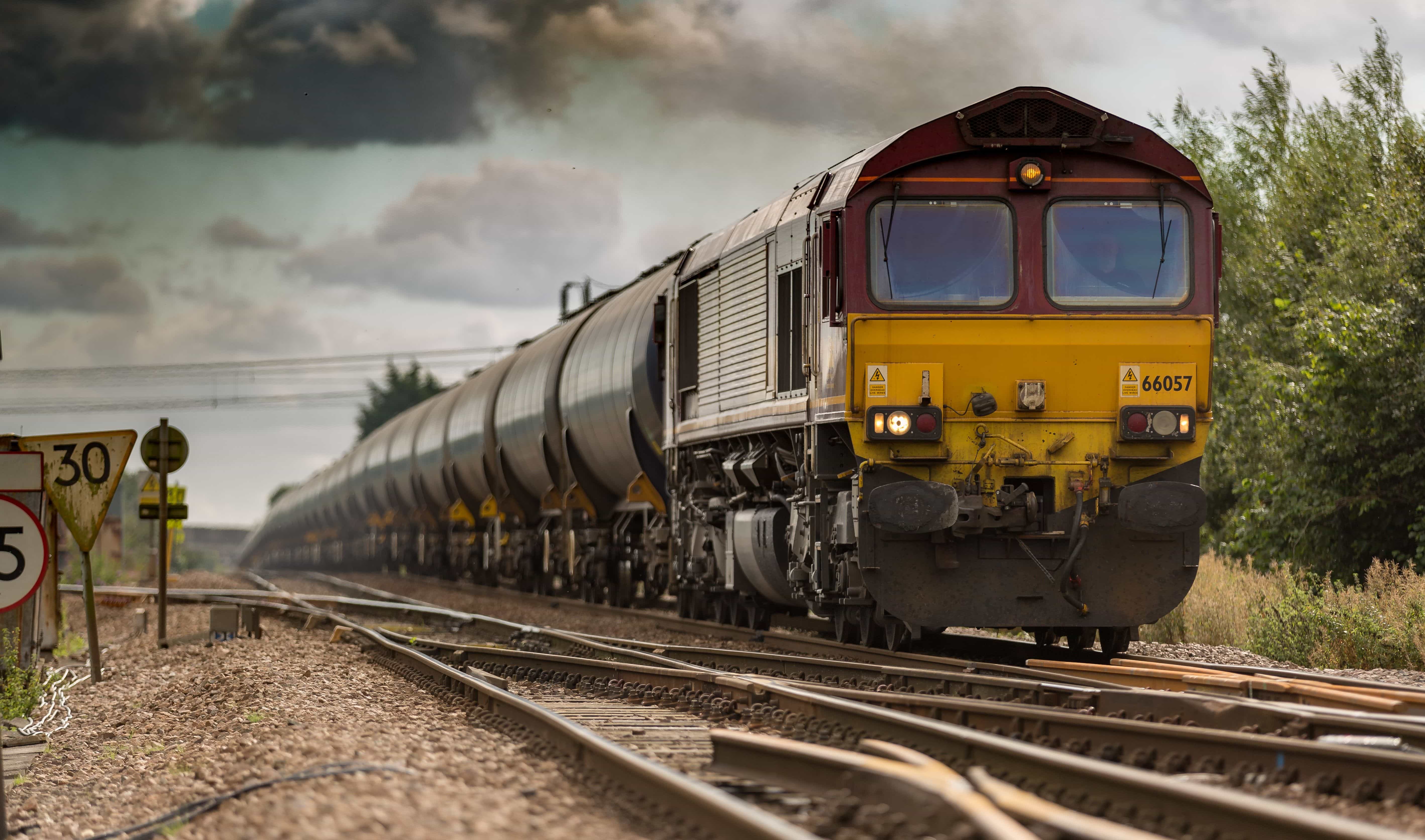 A train moving along the tracks under a cloudy sky.